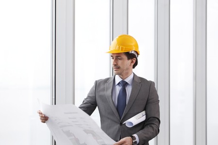Architector in hardhat and business suit with construction plansの写真素材
