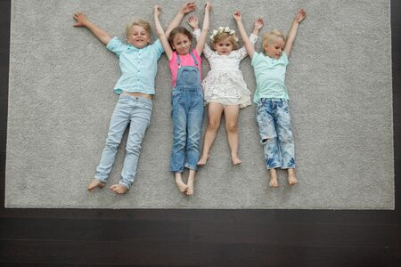 Group of happy kids laying on floor, top viewの写真素材