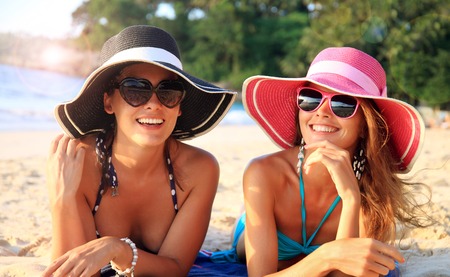 Beautiful young women in sunhats laying on beachの写真素材
