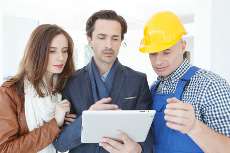 Worker and couple using tablet pc at construction site
