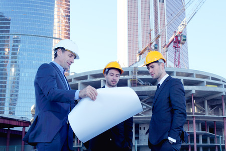 Architects with blueprint at skyscrapers background