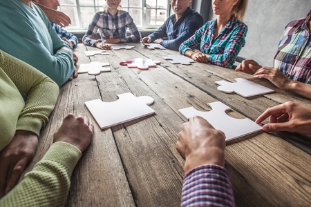 Business people and puzzle on wooden table, teamwork conceptの写真素材