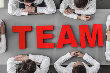 Business people sitting around the table with red letters TEAM, teamwork team work conceptの写真素材