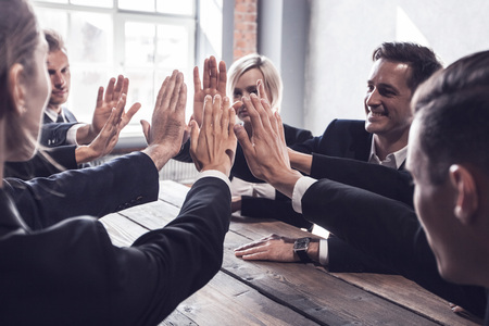 Business people give high five at business meeting