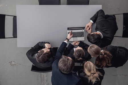 Group of business people look together at laptop in officeの写真素材