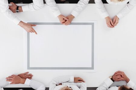 Business team sitting around white table, white copy spaceの写真素材