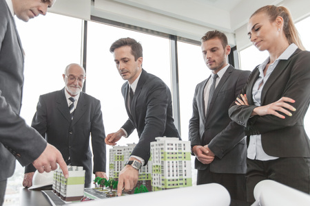Business meeting of architects and investors looking at model of residential quarter housesの写真素材