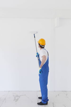 Young worker in hardhats painting the wallの写真素材