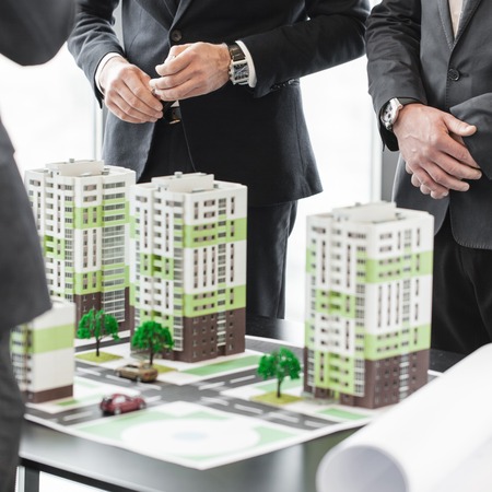 Business meeting of architects and investors looking at model of residential quarter housesの写真素材