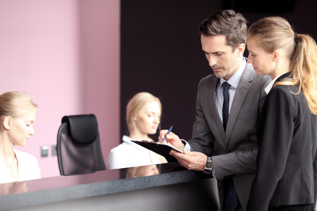 Business people filling forms at front deskの写真素材