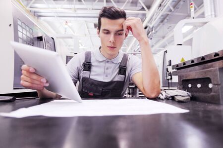 Man working with documents at plant near CNC machinesの写真素材