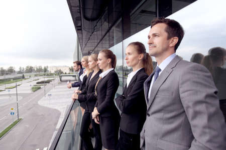 Business team standing on balcony of office buildingの写真素材