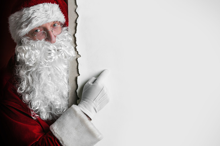 Santa Claus pointing at copy space at big blank cardの写真素材