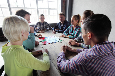Business people and puzzle on wooden table, teamwork concept