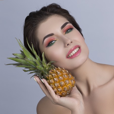 Portrait of a beautiful woman with perfect skin holding pineapple, isolated on white backgroundの写真素材