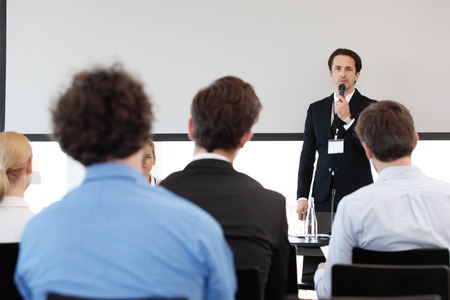 Speaker at business conference near white screen and audienceの写真素材