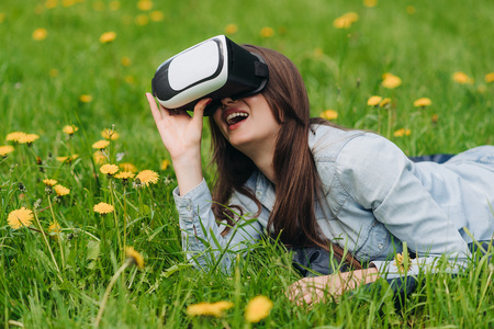 Woman using the virtual reality headset outdoors laying in spring flower fieldの写真素材