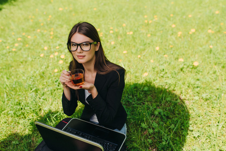 Beautiful business woman in suit using laptop computer in the parkの写真素材