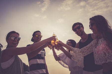 Happy young friends drinking beer outdoorsの写真素材