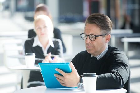 Lot of business people sitting in cafe of modern office buildingの写真素材