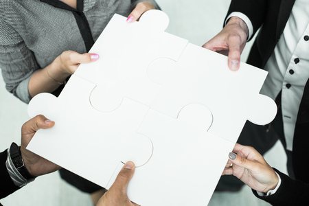 Hands of business people holding white puzzleの写真素材