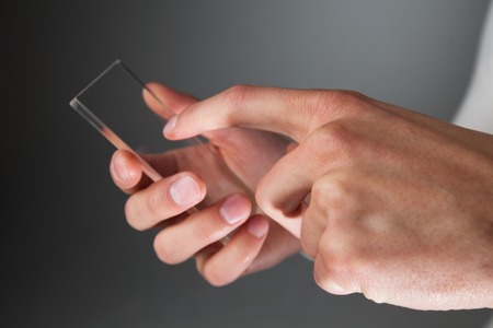 Male hands holding blank futuristic transparent mobile, smart phone with copy spaceの写真素材