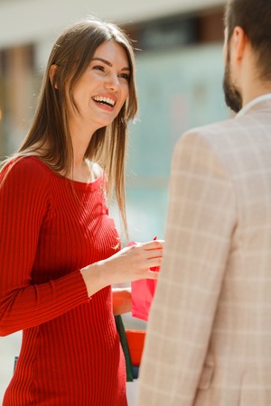 Happy beautiful young couple with gift in shopping mallの写真素材