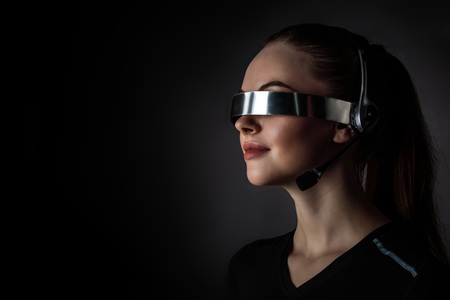 Woman using futuristic VR goggles headset with microphoneの写真素材