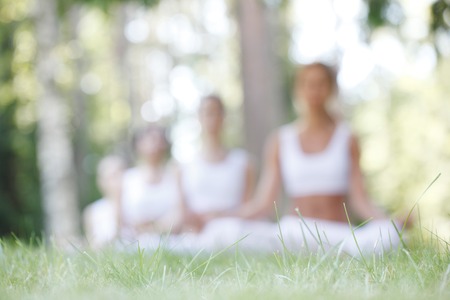 Abstract defocused background of women sitting in lotus position during yoga training at parkの写真素材