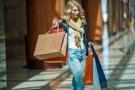 Sale and people - smiling woman with colorful shopping bags over supermarket backgroundの写真素材