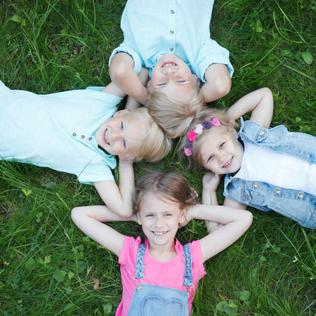 Little friends laying on grass in summer parkの写真素材