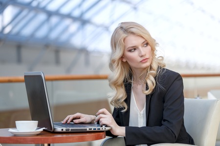 Young business woman wearing suit using laptop computer. Female working on laptop in cafeの写真素材