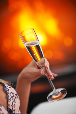 Champagne in woman hand on fireplace backgroundの写真素材