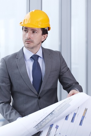 Architector in hardhat and business suit with construction plansの写真素材