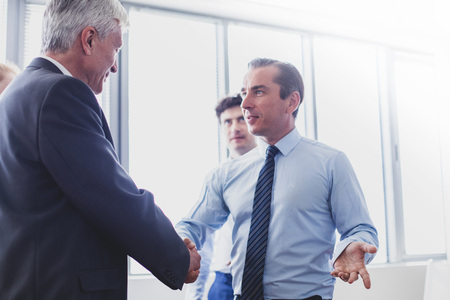 Happy business shaking hands in modern officeの写真素材