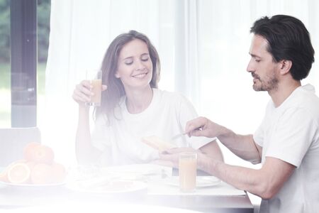 Happy couple having breakfast together at homeの写真素材