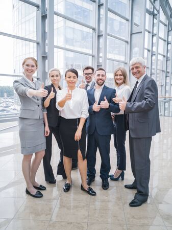 Portrait business people team showing thumbs up , office staff standing in lobbyの写真素材