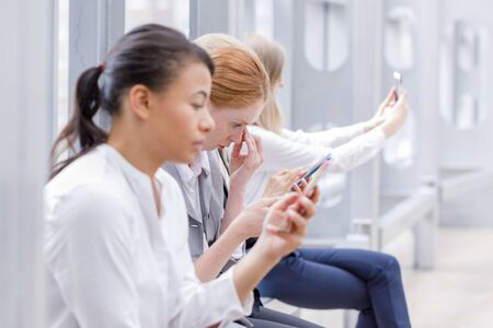 Business people at break with mobile phones surfing the net and taking selfieの写真素材