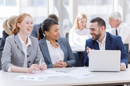 Business team sitting by the table with laptop and documents in office