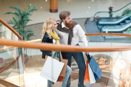 Happy beautiful young couple with shopping bags in mallの写真素材