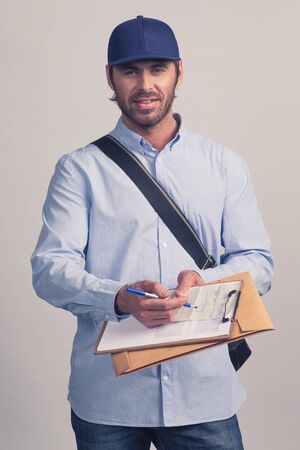 Man in blue uniform holding delivery form on clipboard for delivery