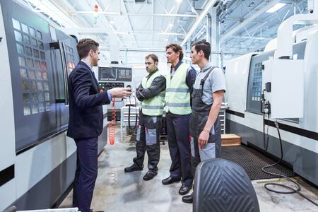 Manager and workers at plant near CNC machines
