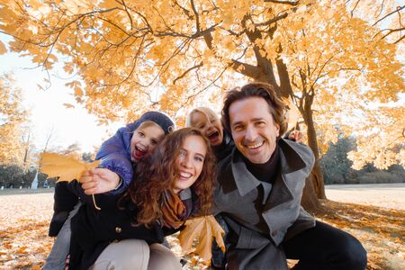 Happy smiling family of parents and children having fun hugging in autumn parkの写真素材