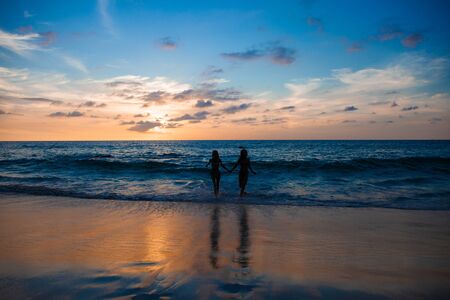Happy female friends having fun on beach at sunsetの写真素材