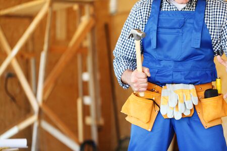 Construction worker in tool belt with hammer at construction siteの写真素材
