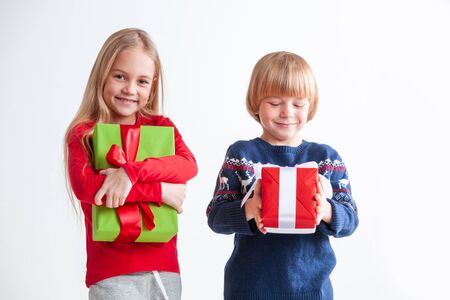 Portrait of two happy children with Christmas gift boxes on white backgroundの写真素材