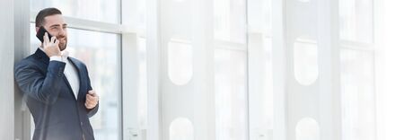 Businessman talking on cell phone in office , white copy space for text contentの写真素材