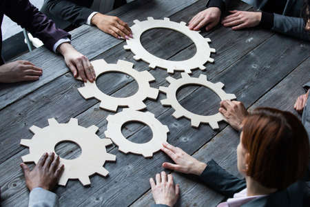 Business people connect golden gear together at meeting table, success cooperation teamwork conceptの写真素材