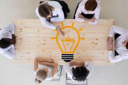 Team of business people pointing idea bulb icon at meeting table strategic marketing creative idea...