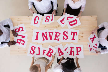 Multi-ethnic group of diverse people putting letters invest investment teamwork cooperation conceptの写真素材